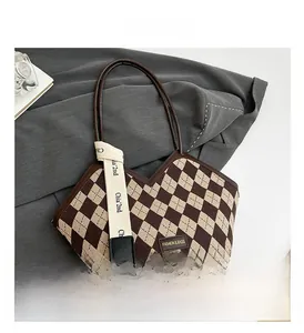 Detail showing checkered knit texture and brown leather strap of this stylish tote bag