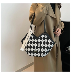 Detail of checkered tote bag with golden metal logo and chic v-shaped top cut design