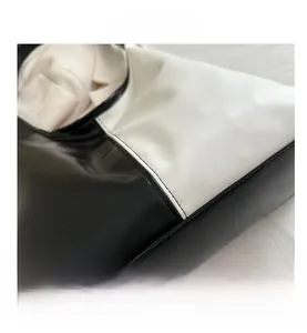 Close-up of contrast stitching on black and white faux leather tote bag with smooth finish
