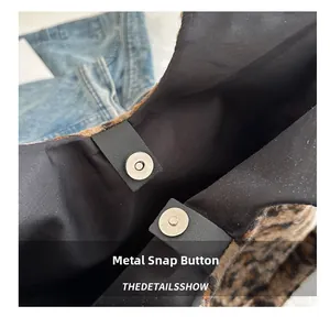 Detailed close-up of the metal magnetic snap closure on the leopard print plush tote bag
