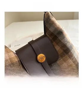 Détail d'un sac à dos à carreaux style britannique avec rabat en cuir et fermoir doré