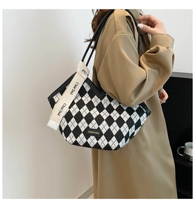 Close-up of black and white checkered tote bag with branded strap and leather tag detail