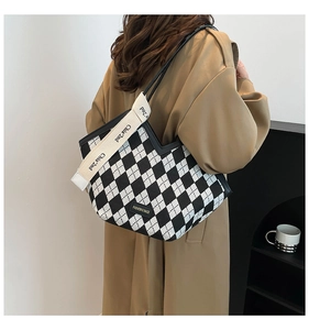 Detail of checkered tote bag with wide canvas shoulder strap and fashion brand logo