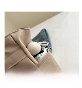 Detail view showing a beige tote bag side pocket with a portable capsule-shaped item