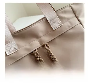 Detail of reinforced stitching and woven zipper pulls on khaki tote bag