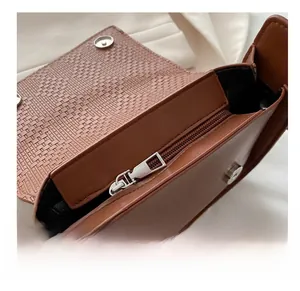 Detail view of the smooth silver zipper and magnetic snap on the brown woven tote bag