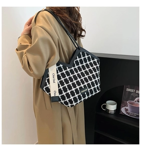 Detail of classic black and white plaid tote bag with V-shaped opening and lettered strap