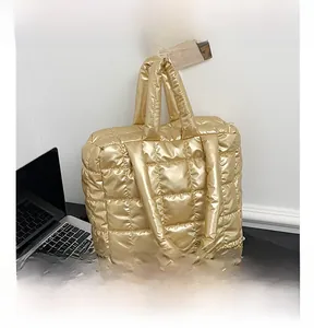 Detail of gold quilted puffer tote bag showing metallic texture next to a laptop