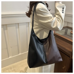 Detailed view of a large two-tone faux leather tote bag worn as a shoulder underarm bag