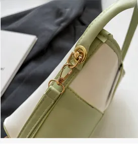 Detail of golden metal buckles and handle attachments on bi-color bucket handbag