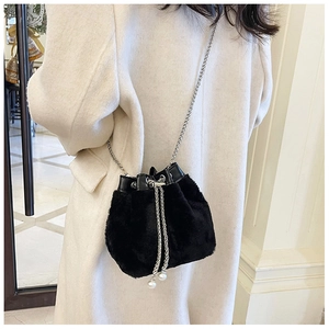 Détails d'un sac seau noir en peluche avec chaîne argentée et perles sur le cordon