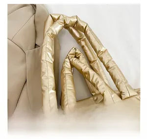 Macro detail of golden quilted tote bag showing the metallic texture and padded handle