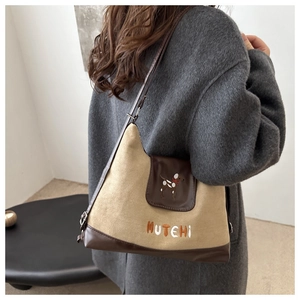Detail of retro khaki tote bag featuring leather trim and MUTEHI puppy embroidery