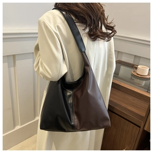 Detailed side view of a large hobo shoulder bag in brown and black leather on a model