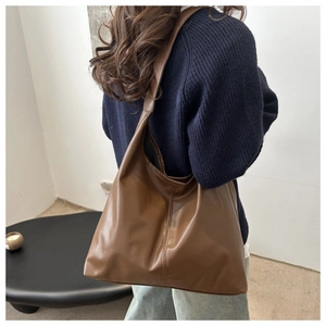 Close-up of a dark brown large capacity faux leather tote bag worn on shoulder