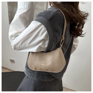 Dettaglio borsa hobo beige con trama a serpente e fibbia ad anello dorato sulla tracolla