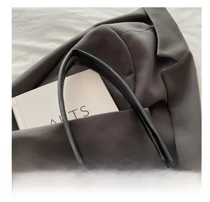 Close-up of comfortable black leather handle with a grey blazer and an artsy book