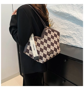 Detailed view of checkered crossbody bag with leather trim and wide canvas shoulder strap