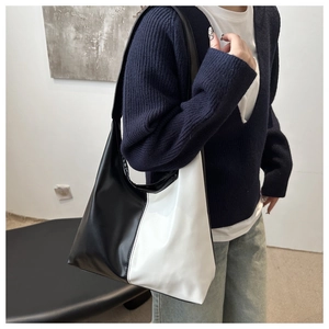 Side view of a large black and white contrast hobo shoulder bag worn by a model