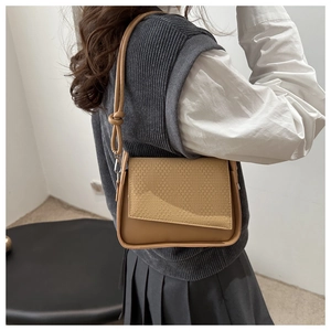 Detailed view of woven texture flap and knot detail on khaki crossbody handbag