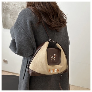 Detail of crossbody bag with beige suede and brown leather featuring a puppy embroidery