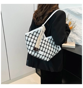 Detail of black and white checkered tweed tote bag with elegant white leather strap