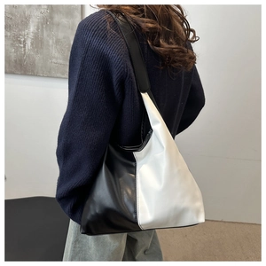 Detailed side view of a large black and white contrast leather hobo bag worn by model