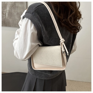 Detail of a beige woven textured handbag with a unique knotted shoulder strap