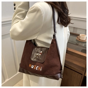 Close-up of brown suede crossbody bag with dog embroidery and MUTEHI text detail