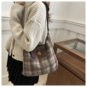 Détail du sac bandoulière à carreaux avec rabat en cuir et boucle dorée lettre N