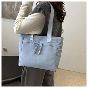 Detail showing the light blue tote bag side pockets and textured woven zipper pulls