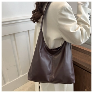 Detail view of dark brown faux leather tote bag with elegant side stitching on model