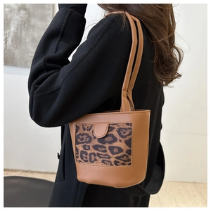 Brown bucket bag with leopard print pocket styled with a black coat on the shoulder
