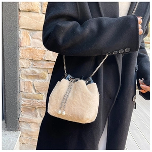 Détail du sac seau en peluche avec chaîne et cordon perlé sur un manteau en laine noir