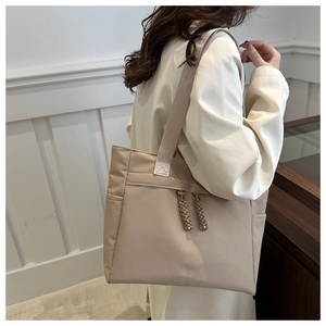 Beige tote bag worn over the shoulder with a long coat for a stylish commuter look