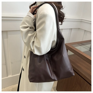 Detail of soft dark brown leather texture and stitching on large shoulder tote bag