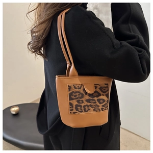 Fashionable leopard print bucket bag styled with a black coat in a minimalist interior