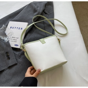 Detail of a chic two-tone bucket bag featuring white leather and pale green accents