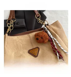 Détail du sac cabas en toile kaki avec anses en cuir et breloque ours en peluche