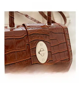 Détail de la texture croco marron et du fermoir rotatif en métal argenté sur le sac à main