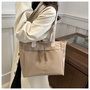 Detail of minimalist beige tote bag with woven zipper pull and functional side pocket