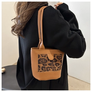 Detailed side view of a brown bucket bag with leopard print pocket on black coat