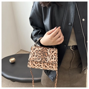 Gros plan du sac bandoulière léopard porté avec veste en cuir et jupe en daim chic