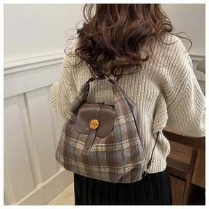 Détail de la texture du tissu à carreaux et rabat en cuir avec boucle dorée du sac à dos