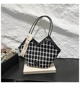 Detailed macro view of black and white checkered tweed tote with leather trim and fashion label