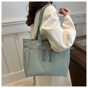 Detail of light green tote bag with braided rope handles and functional side pocket