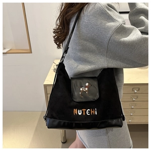 Detail of black canvas shoulder bag featuring an embroidered dog pattern and MUTEHI text