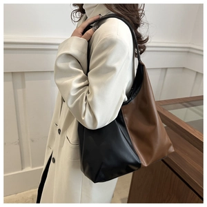 Side view of large bicolor tote bag in black and brown faux leather on female model