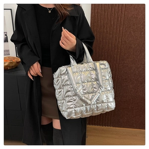 Detail of silver metallic quilted tote bag with lattice pattern on a female model