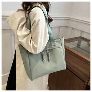 Detail view of the mint green tote bag featuring woven drawstrings and side pocket texture